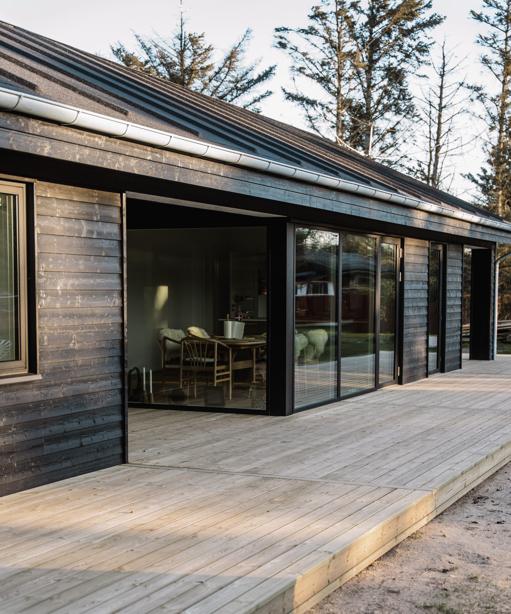 Arkitekttegnet sommerhus i sort træ i gyldent aftenlys.