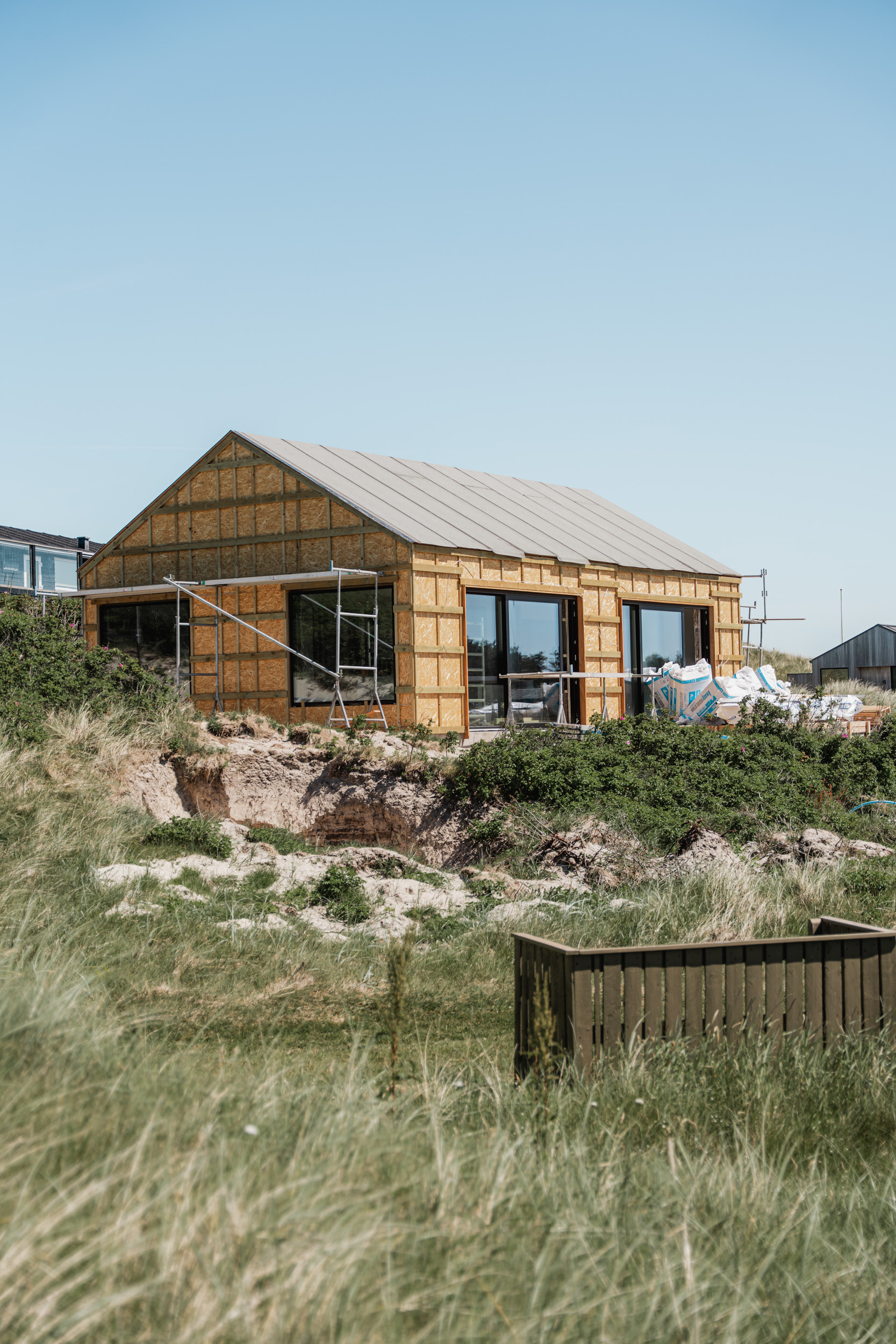 Sommerhus under opførelse på grunden — råhus med tag